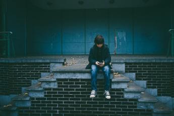 photo of a child sitting alone outside an abandoned building