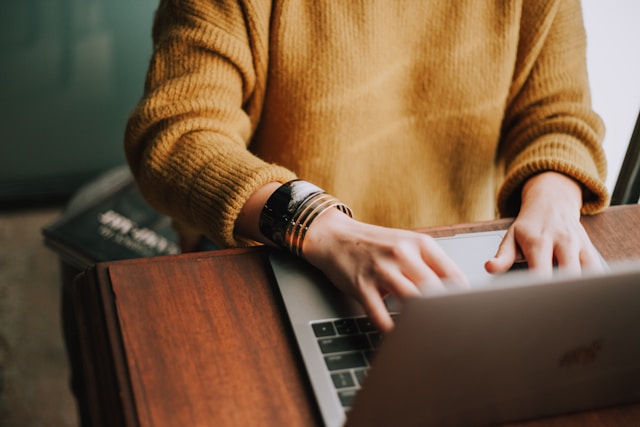 closeup photo of a person's hands typing on a laptop