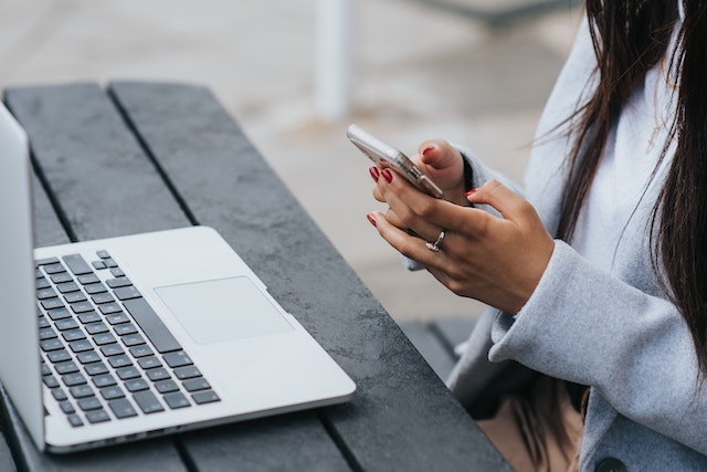 ethnic businesswoman chatting on smartphone near laptop on table