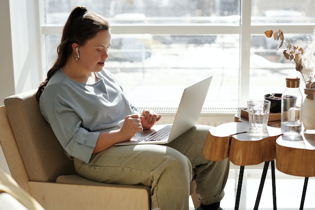 woman with a disability sitting on a chair with a laptop reading