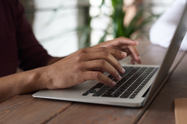 photo of a person's hands typing on a laptop