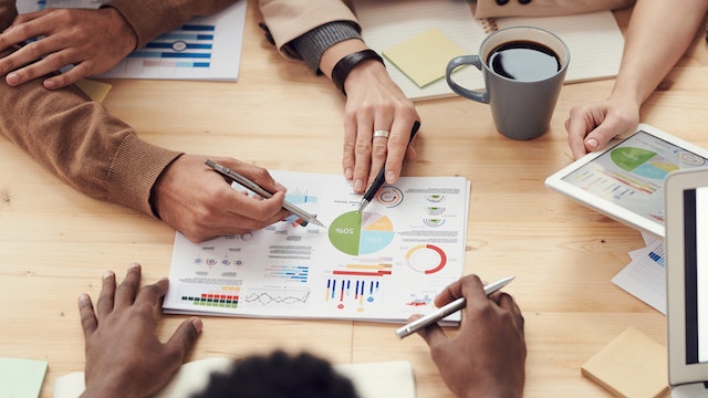 people pointing at paperwork on a table