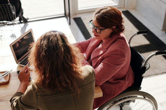 two women talking, one woman in a wheelchair