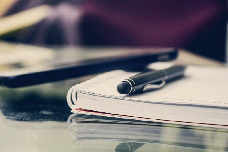 a pen sitting on a notebook with a mobile phone