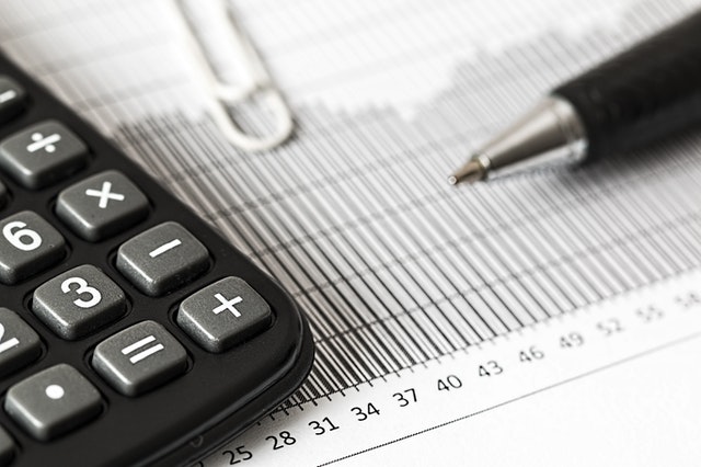 photo of calculator on top of piece of paper with calculations and a pen