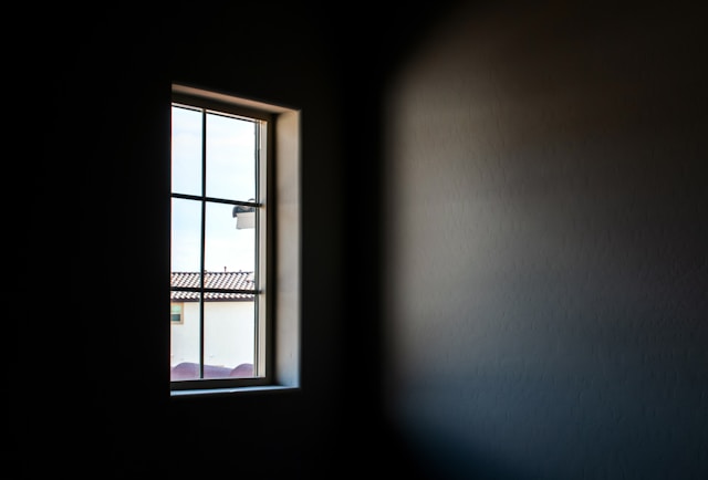 photo of a window with light shining in on an empty wall